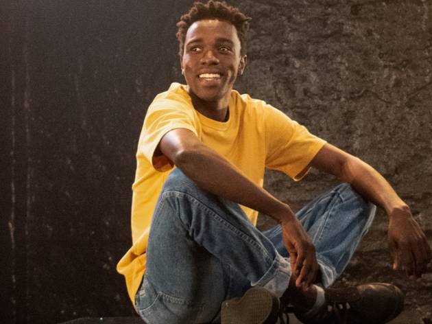Jali, Griffin 2021 Oliver Twist sits cross-legged, wearing jeans and a yellow tee