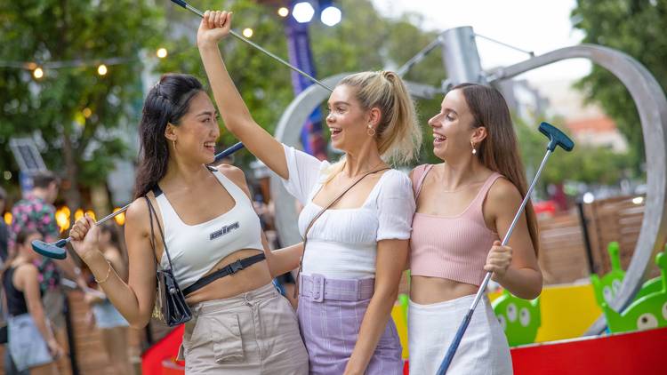 Three women celebrate at Pixar Putt