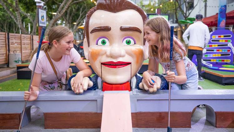 Two girls play mini golf at Pixar Putt