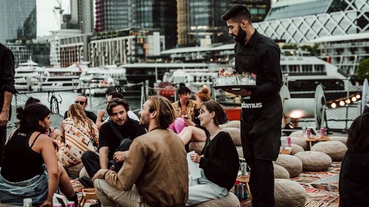 Waiter brings drinks to people picnicing on ship