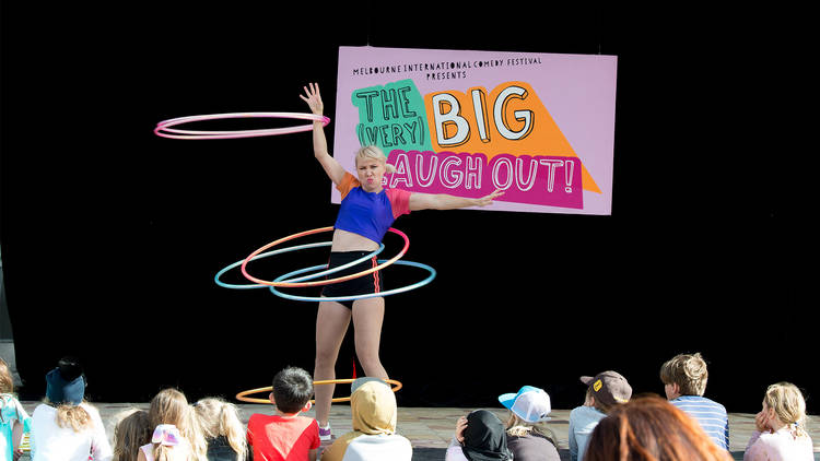 A performer entertains a crowd of kids with an impressive amount of hula hoops