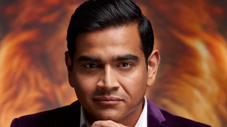 A close-up of comedian Dilruk Jayasinha in a purple velvet jacket 