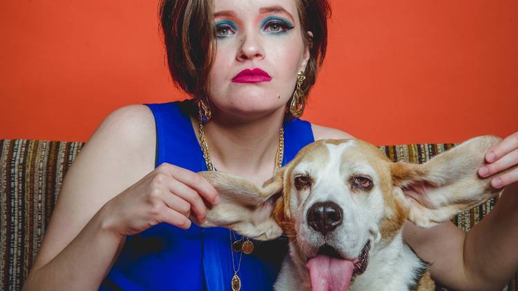 Alice Tovey, in a bright blue top, holds a dog's ears