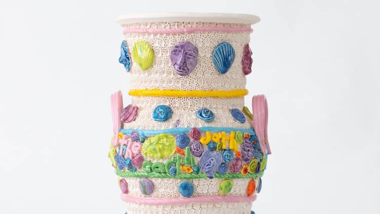 A cute ceramic urb in pastel shades with faces and flowers adorning it