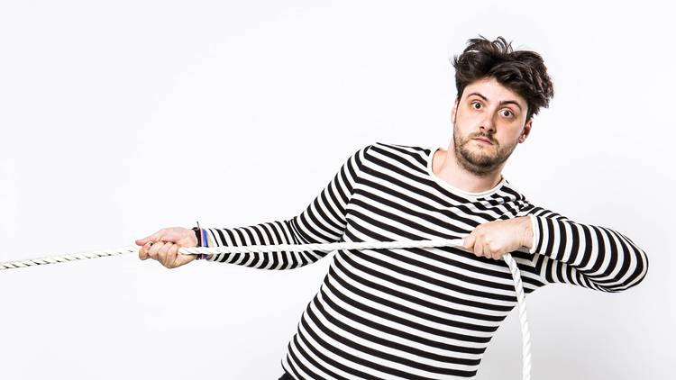 A person wearing a black and white striped shirt pulls a white rope from out of the frame