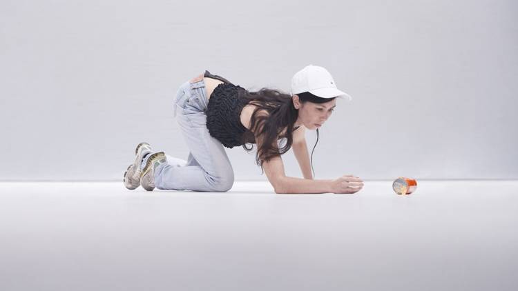 Dancer Angela Go kneeling on the floor in front of a spilled can 