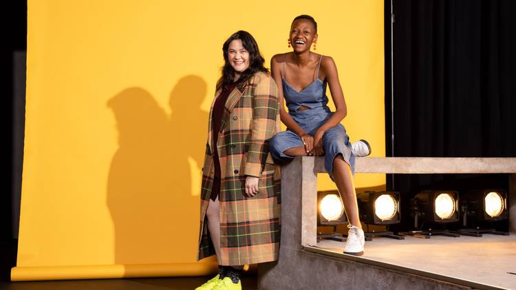 Moreblessing Maturure and Shari Sebbens laugh, set against a yellow backdrop