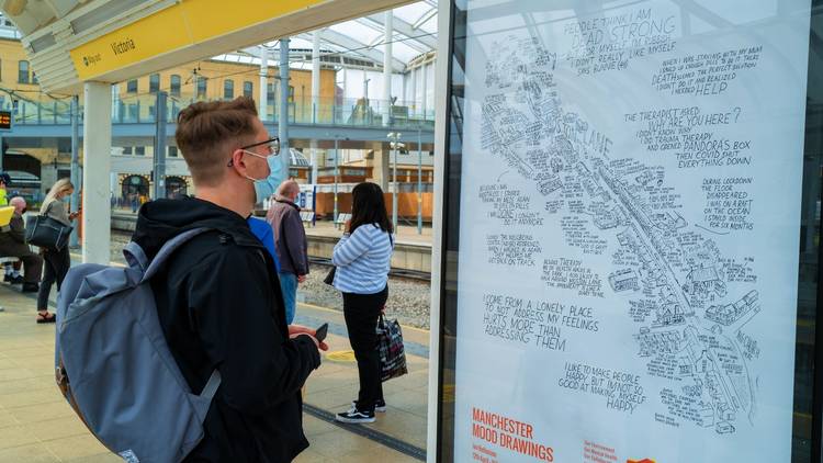 A young man looks at a Mood Drawing poster at Victoria's Metrolink Station