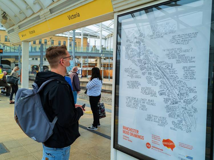 A young man looks at a Mood Drawing poster at Victoria's Metrolink Station