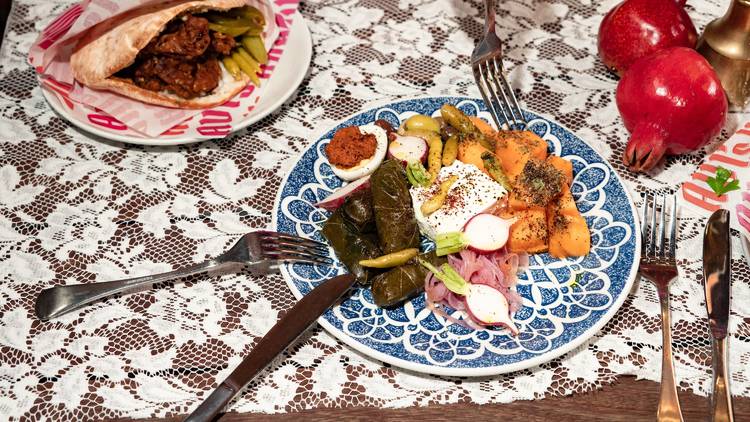 Plate of food with dips and pickles on a white tablecloth