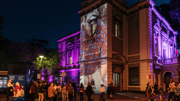 Leichardt Town Hall with purple and video projections on its facade at night. 