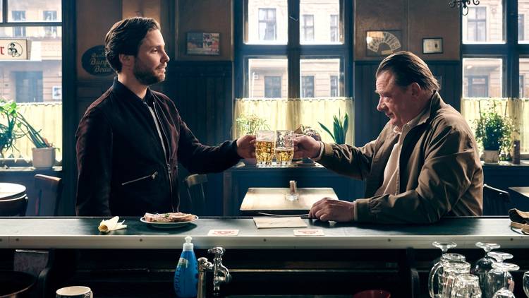 two men cheers with beer in a bar