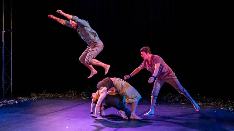 a man leaps over two women