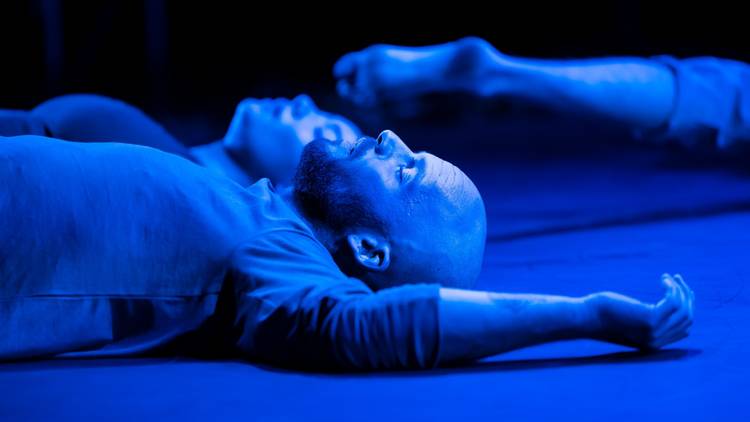 a man resting on the floor is bathed in blue light