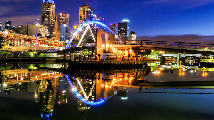 The Yarra river at night with Melbourne skyline and bridge lit up.