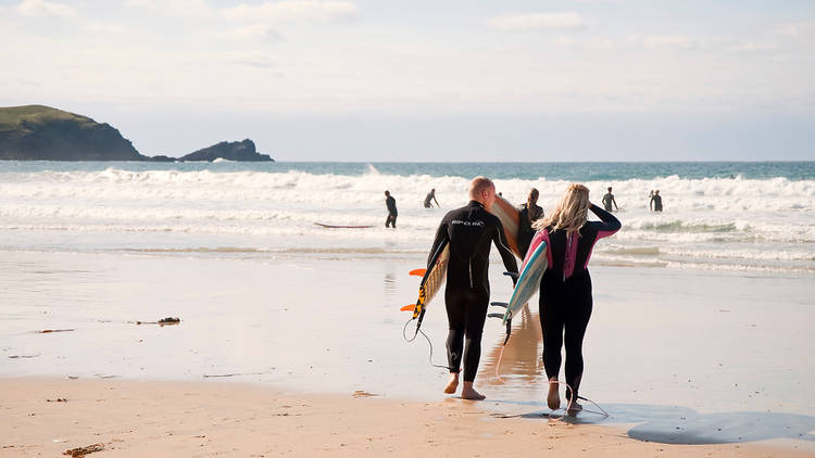 Surfers entering the water on Fistral Beach in Cornwall