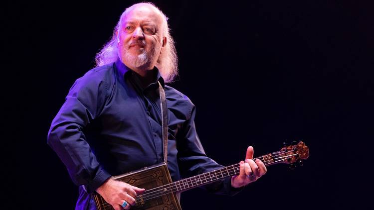 Comedian Bill Bailey on stage playing a guitar made out of a book