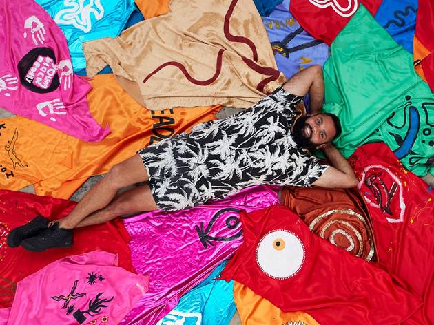 The Future is Here, Carriageworks 2021 First Nations artist Dennis Golding lies on a bed of superhero capes designed by school kids