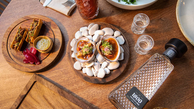 Mesa de restaurante con platillos servidos y botella de tequila