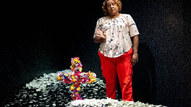 Elaine Crombie stands at a piles of shells with a colourful cross