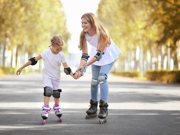 Mother,With,Daughter,Rollerskating,In,Park Mother with daughter rollerskating in park