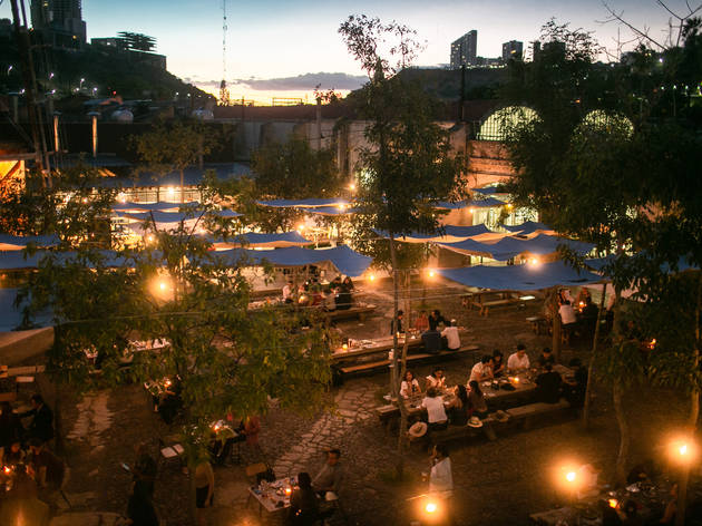 Jardín Hércules Patio con mesas y techos en atardecer con luces encendidas
