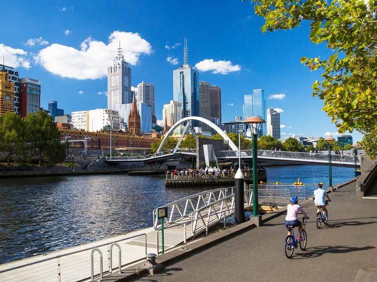 Two people rides bikes next to the Yarra River in Melbourne's CBD, near Ponyfish Island.