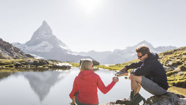 Two people sit and relax by Lake Riffelsee in Zermatt.