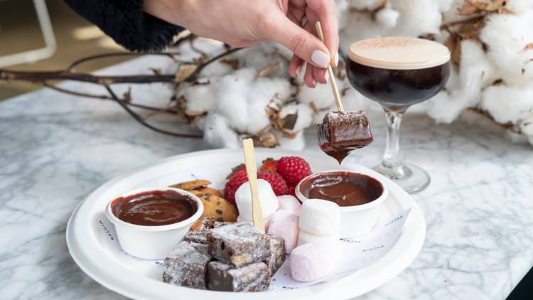 Person dipping marshmallow into chocolate