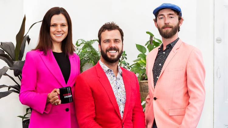 Two men and a woman wear brightly coloured blazers while smiling at the camera