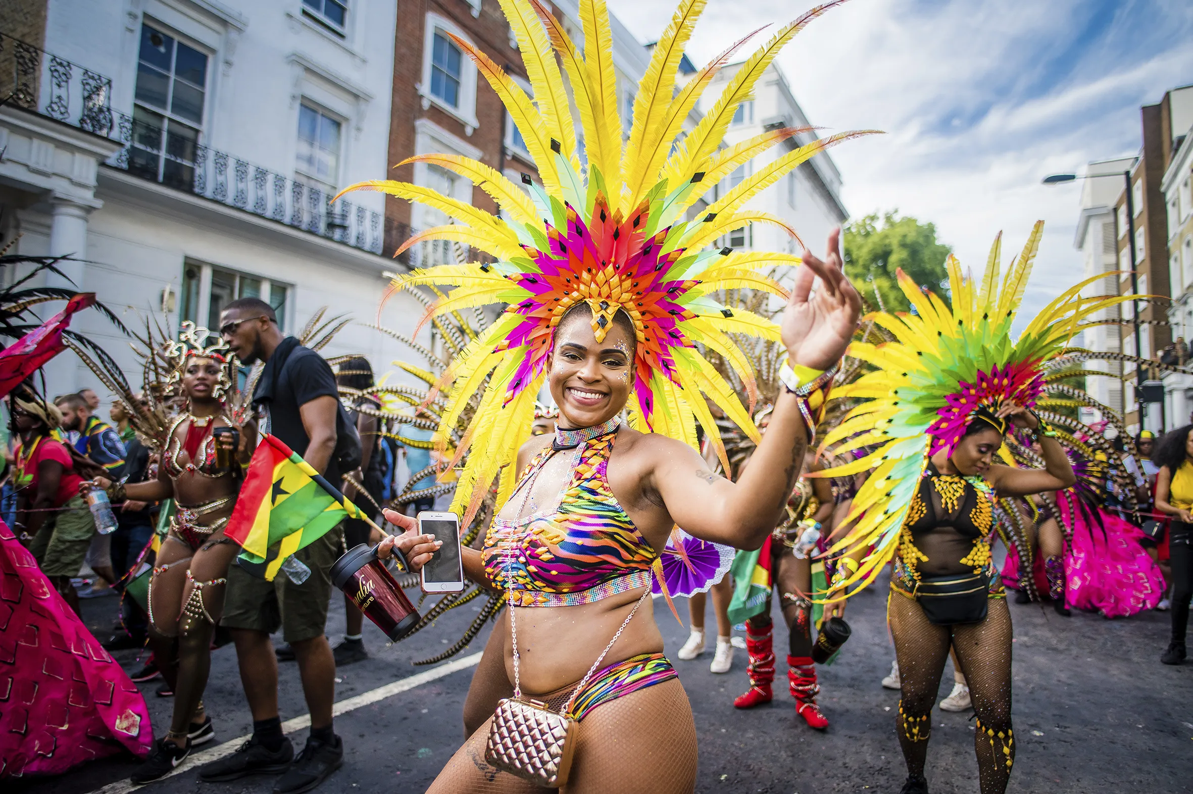 A woman wearing an elaborate yellow feathered headdress dancing at Notting Hill Carnical