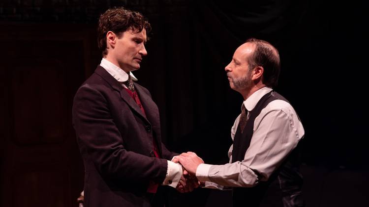 Two men in Victorian tailoring clasp hands together