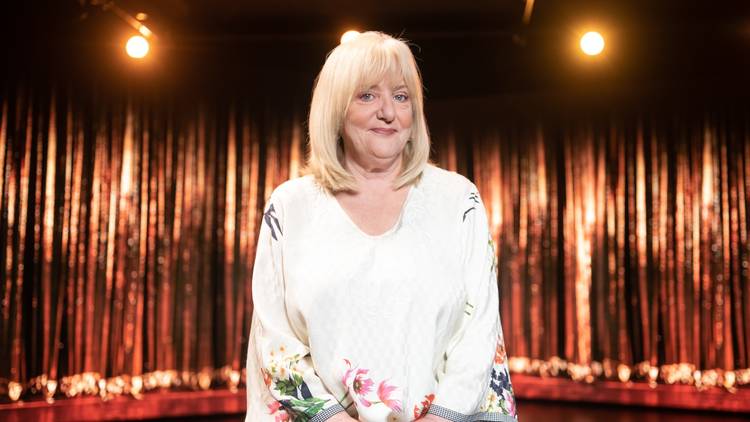 Comedian Denise Scott in front of showbiz curtains