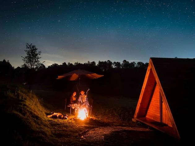 Glamping Canto del Bosque Dos personas en frente de una fogata en el atardecer