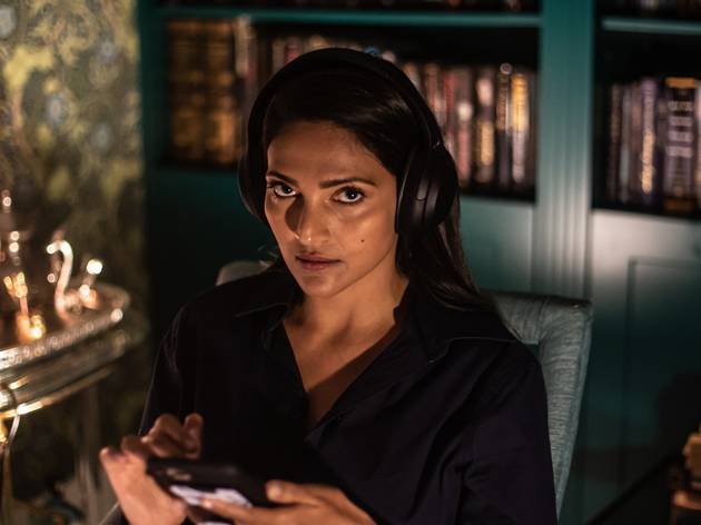 Darkfield Radio a woman in a candlelit room with bookshelves listens to a scary Darkfield Radio show