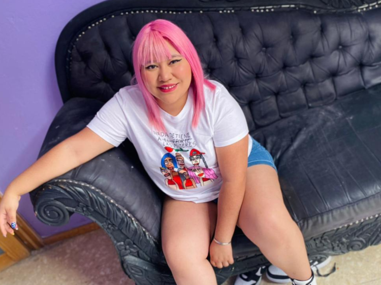 Fotografía de mujer Herly RG sentada en sillón negro y cabello rosa