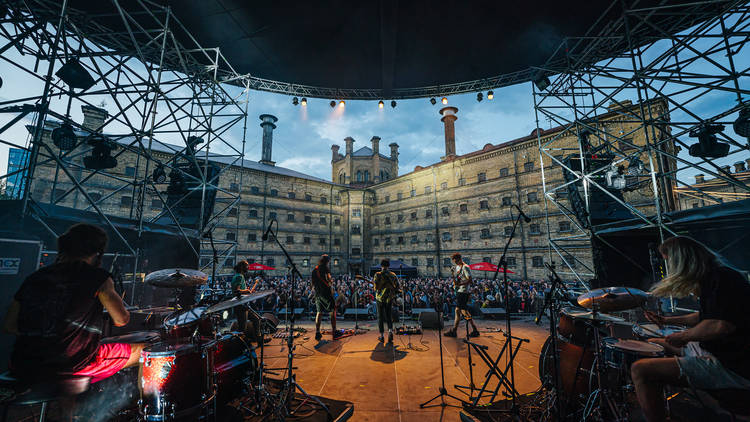 Two guitarists and two drummers on a stage in the grounds of a former prison in Vilnius