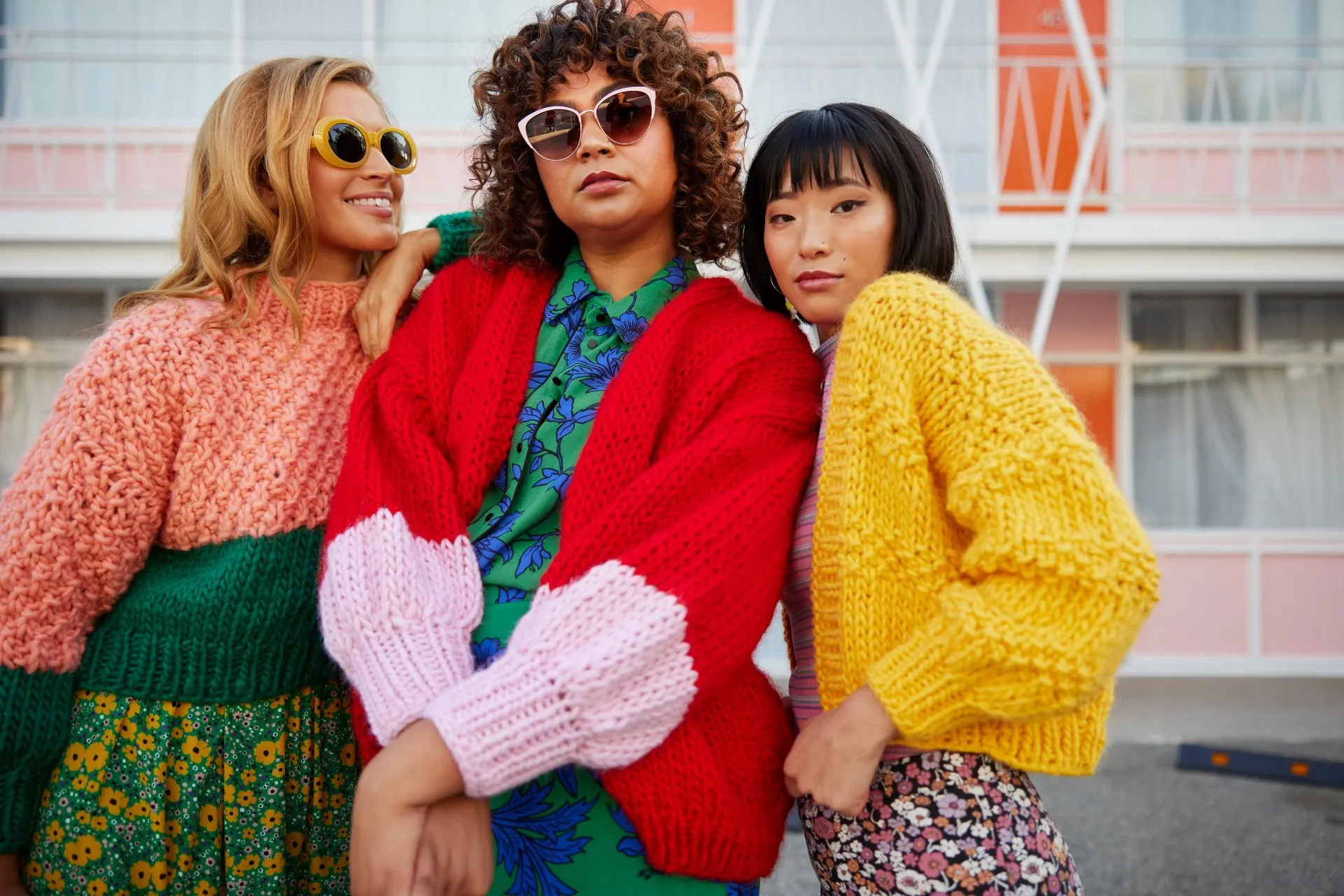 Three fabulous looking people wearing bright, hand-knitted jumpers.