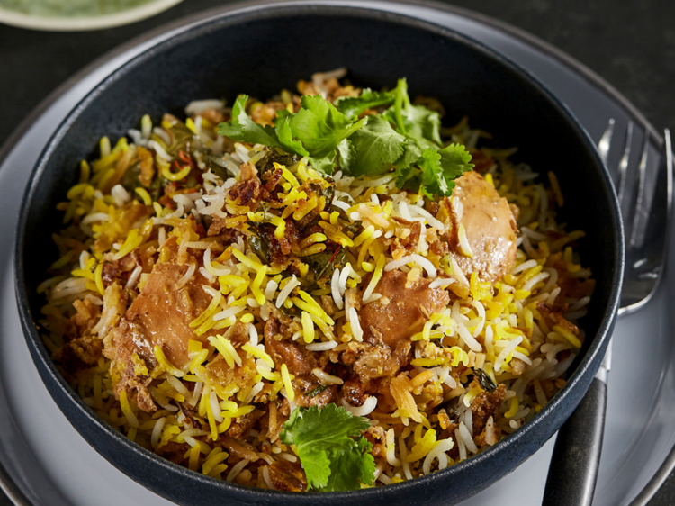 A bowl of yellow and white rice biriyani with chicken 