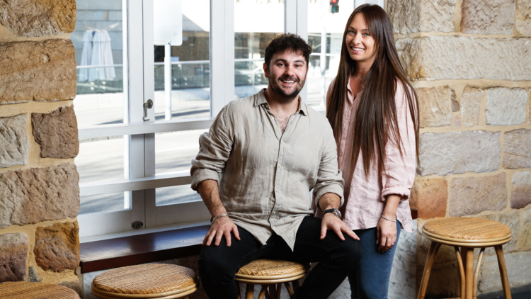 Quick Brown Fox owners Ben Calabro and Anna Mavromatis pole in front of a sandstone wall