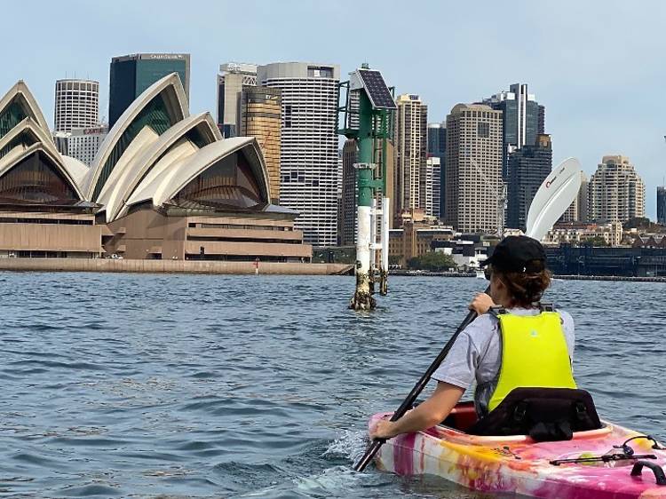 A kayak paddling in front of the Sydney Opera House