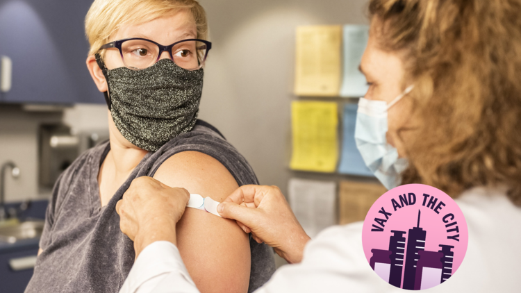 A person wearing a mask has a bandaid put on their arm following a vaccination