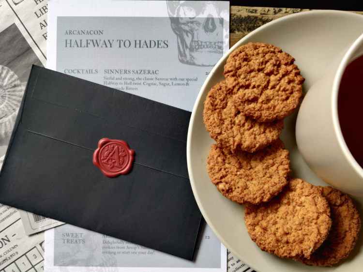 An envelope and newspaper with a plate of cookies and a tea on top. 