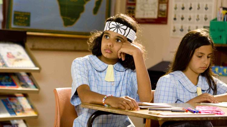 Still from the film 'Ralph', in which a young girl in a classroom sits at a desk, wondering