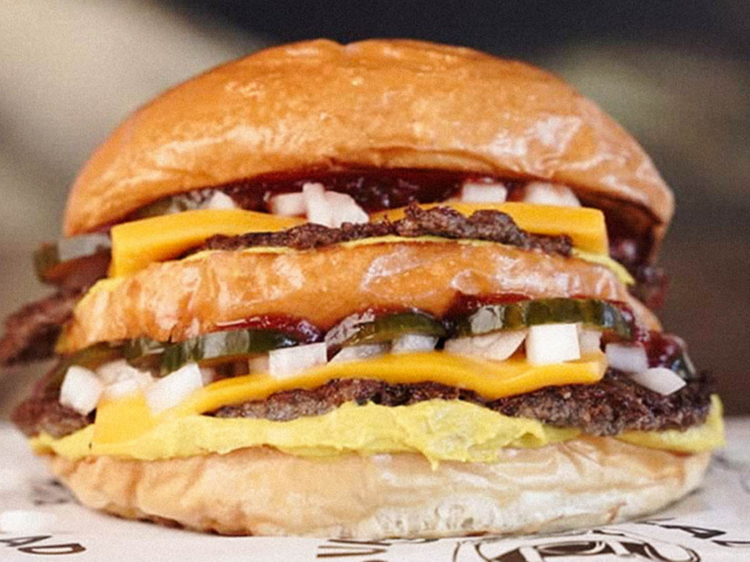 A three layer cheese burger on a black and white sheet of paper