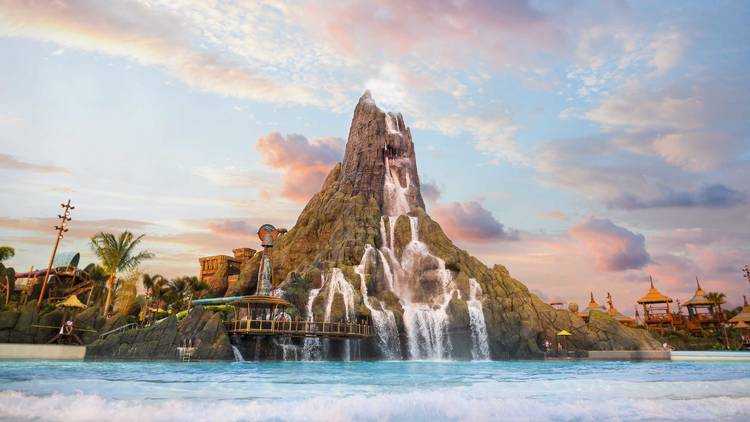 A volcano rising from the ground with a wave pool in front