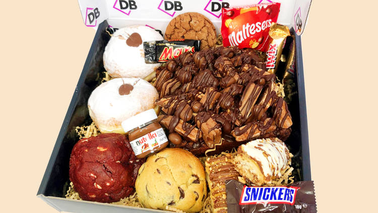 A box with doughnuts, Nutella, Snickers, cookies, a giant brownie slab and more.