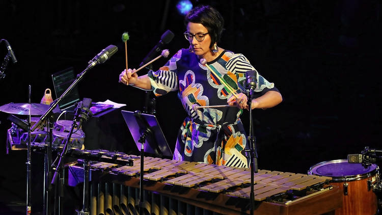 A woman in a colourful dress plays a large xylophone