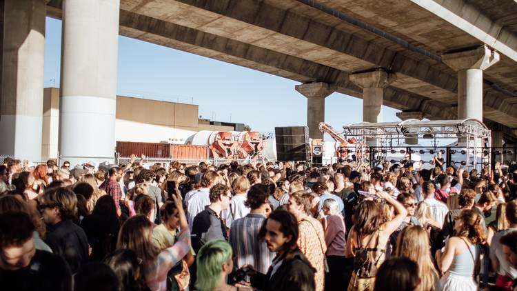 A crowd of people partying under the western freeway overpass in port melbourne