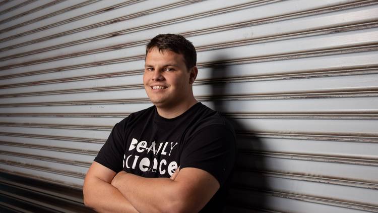 Corey Tutt, founder of Deadly Science, leaning against a corrugated shutter
